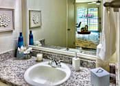 Thumbnail 13 of 47 - Bathroom in an Efficiency apartment at Cambridge Court Apartments in Dallas, Texas, featuring a vanity, mirror, toilet, and tub/shower combination.
