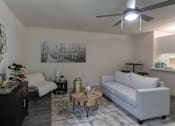 Thumbnail 20 of 47 - Staged living room in a 1-bedroom apartment at Cambridge Court Apartments in Dallas, Texas, featuring wood-style flooring, neutral walls, ceiling fan, and open connection to the kitchen.