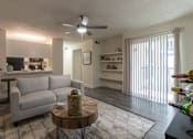 Thumbnail 19 of 47 - Living room view in a 1-bedroom apartment at Cambridge Court Apartments in Dallas, Texas, showing staged seating, wood-style flooring, patio door, and connection to the kitchen.