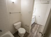 Thumbnail 29 of 40 - A white toilet in a small bathroom with a white tiled shower.