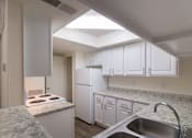 Thumbnail 8 of 40 - A kitchen with white cabinets and appliances in a 717 square foot 1 bedroom, 1 bath loft apartment home at Canyon Creek Apartments in Dallas Midtown neighborhood of Dallas, TX.