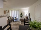 Thumbnail 15 of 40 - View of the living room with a couch, chaise lounge and a potted plant from the dining room of a 515 square foot 1 bedroom, 1 bath apartment home at Canyon Creek Apartments in Dallas Midtown neighborhood of Dallas, TX.