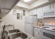 Thumbnail 2 of 40 - A kitchen with a white cabinets and appliances in a 515 square foot 1 bedroom, 1 bath apartment home at Canyon Creek Apartments in Dallas Midtown neighborhood of Dallas, TX.