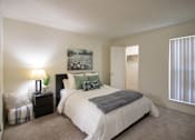 Thumbnail 18 of 40 - A bedroom with a large bed and a painting on the wall in a 515 square foot 1 bedroom, 1 bath apartment home at Canyon Creek Apartments in Dallas Midtown neighborhood of Dallas, TX.