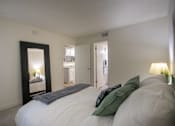 Thumbnail 19 of 40 - A bedroom with a large painting and a large mirror leaning against the wall in a 515 square foot 1 bedroom, 1 bath apartment home at Canyon Creek Apartments in Dallas Midtown neighborhood of Dallas, TX.