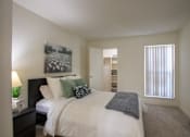 Thumbnail 20 of 40 - A bedroom with a large painting and a large mirror leaning against the wall in a 515 square foot 1 bedroom, 1 bath apartment home at Canyon Creek Apartments in Dallas Midtown neighborhood of Dallas, TX.