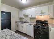 Thumbnail 6 of 41 - Bright kitchen with white cabinets and black appliances in a two-bedroom, two-bath apartment home