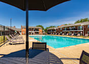 Thumbnail 34 of 41 - Pool deck seating area with umbrella tables overlooking the community swimming pool