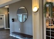 Thumbnail 69 of 74 - A room with a round mirror and a bench.