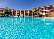 Thumbnail 8 of 59 - Community pool with clear blue water and surrounding apartment homes at Lake of the Woods Apartments