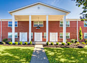 Thumbnail 56 of 59 - Brick apartment building with covered entry and central sidewalk at Lake of the Woods Apartments