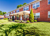 Thumbnail 58 of 59 - Brick apartment building with landscaped entry, green lawn, and shade trees at Lake of the Woods Apartments