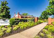 Thumbnail 51 of 59 - Community entrance sign with fresh landscaping and sidewalk at Lake of the Woods Apartments