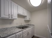 Thumbnail 5 of 62 - A kitchen with a white cabinets 1 bedroom, 1 bath apartment home at Princeton Court Apartments in the Vickery Midtown neighborhood of Dallas, TX.