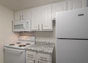 Thumbnail 29 of 62 - A kitchen with a white cabinets and white appliances 1 bedroom, 1 bath apartment home at Princeton Court Apartments in the Vickery Midtown neighborhood of Dallas, TX.