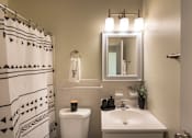 Thumbnail 25 of 38 - A bathroom with a white sink, toilet, and a mirror above it.