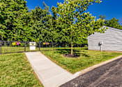 Thumbnail 65 of 96 - A sign is on a fence in front of a green tree.