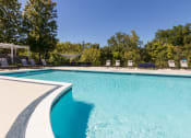 Thumbnail 16 of 98 - a swimming pool with chairs and trees in the background