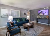 Thumbnail 36 of 44 - The leasing office with a blue couch and a television on the wall at The Summit at Midtown Apartments in Midtown, Dallas, TX.