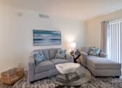 Thumbnail 8 of 44 - A modern living room with a grey sofa, chaise lounge and a glass coffee table in the 558 square foot 1 bedroom, 1 bath model apartment at The Summit at Midtown Apartments in the Dallas Midtown neighborhood of Dallas, TX.