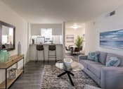 Thumbnail 7 of 44 - A modern living room with a grey sofa and a glass coffee table in the 558 square foot 1 bedroom, 1 bath model apartment at The Summit at Midtown Apartments in the Dallas Midtown neighborhood of Dallas, TX.