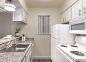 Thumbnail 6 of 43 - alley kitchen with white cabinets, granite-style countertops, electric range, and refrigerator in a 558-square-foot one-bedroom apartment