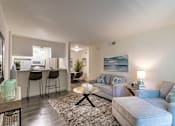 Thumbnail 7 of 43 - Open living room with sectional seating, wood-look flooring, and breakfast bar in the 558-square-foot 1 Bedroom, 1 Bath A