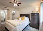 Thumbnail 14 of 43 - A bedroom with a bed, dresser, and ceiling fan.