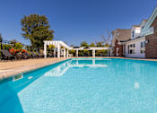 Thumbnail 16 of 75 - A swimming pool in front of a house with a white pergola.