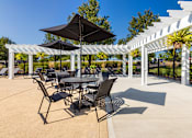 Thumbnail 46 of 75 - A patio with a table and chairs under a black umbrella.
