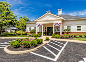 Thumbnail 54 of 61 - A building with a flag on the front and a parking lot in front of it.