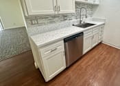 Thumbnail 37 of 55 - a kitchen with white cabinets and a stainless-steel dishwasher  at Willow Tree Apartments, California, 90505