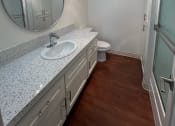 Thumbnail 30 of 36 - a bathroom with a sink and a toilet and a mirror at Copa Ladeene Apartments, Torrance California