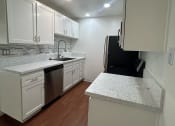 Thumbnail 20 of 36 - an empty kitchen with white cabinets and a counter top at Copa Ladeene Apartments, Torrance California