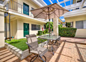 Thumbnail 8 of 19 - a patio with an umbrella and a table with chairs at Olive Tree Apartments, Torrance, CA 90503