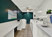 Thumbnail 10 of 19 - a laundry room with a row of sinks and a ceiling fan at Olive Tree Apartments, California