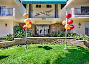 Thumbnail 12 of 19 - a yard with grass and balloons in front of a building at Olive Tree Apartments, Torrance, CA 90503