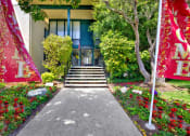 Thumbnail 12 of 36 - a path leading up to a building with flowers and trees at Casa Del Amo Apartments, Torrance, CA