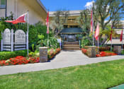 Thumbnail 1 of 54 - the front of a building with flags and a sidewalk at Camino de Oro Apartments, Torrance, CA