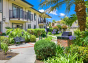 Thumbnail 8 of 54 - a courtyard with benches and plants in front of an apartment building at Camino de Oro Apartments, Torrance, CA, 90505
