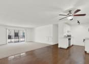 Thumbnail 34 of 54 - an empty living room with a ceiling fan and a kitchen at Camino de Oro Apartments, Torrance, California