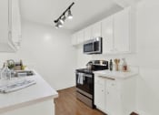 Thumbnail 41 of 54 - a white kitchen with white cabinets and a black microwave at Camino de Oro Apartments, Torrance, CA