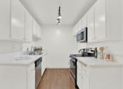 Thumbnail 43 of 54 - a kitchen with white cabinets and a stove and a microwave at Camino de Oro Apartments, Torrance, CA, 90505