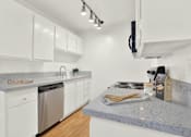 Thumbnail 40 of 54 - a kitchen with granite counter tops and white cabinets at Camino de Oro Apartments, Torrance, California