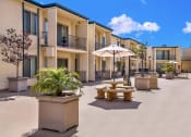 Thumbnail 10 of 36 - a courtyard with tables and umbrellas in front of apartments at Casa Del Amo Apartments, Torrance