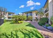 Thumbnail 8 of 36 - a yard with grass and palm trees in front of an apartment building at Casa Del Amo Apartments, Torrance California
