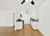 Thumbnail 32 of 36 - a kitchen with white cabinets and a wood floor at Casa Del Amo Apartments, California