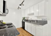Thumbnail 23 of 36 - a kitchen with white cabinets and granite counter tops at Casa Del Amo Apartments, Torrance, 90505