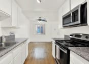 Thumbnail 24 of 36 - a kitchen with granite counter tops and black appliances at Casa Del Amo Apartments, Torrance, CA 90505