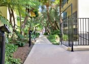 Thumbnail 2 of 26 - a sidewalk in front of a building with trees and plants at Casa De Oro Apartments, Torrance California